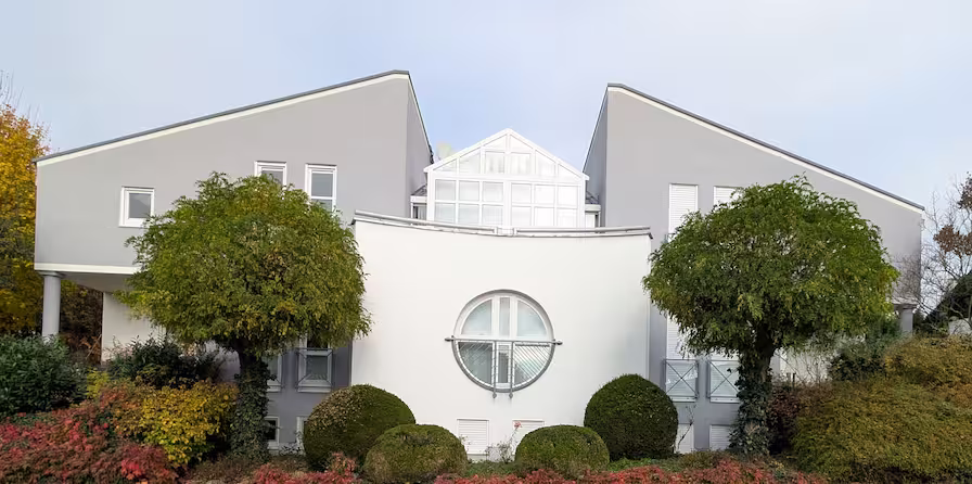 Helle Villenfassade mit klar abgesetzten grauen Elementen